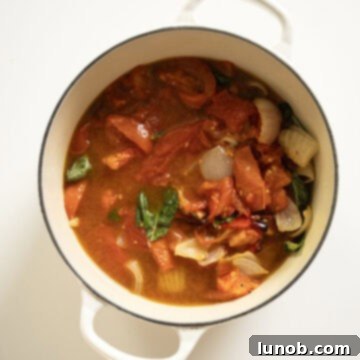 Rich Roasted Garlic and Tomato Cream Soup 8 Roasted tomatoes, onions, and red pepper are carefully added to a pot of simmering chicken broth, with fresh basil leaves ready to be torn in, and the roasted garlic being squeezed into the mixture.