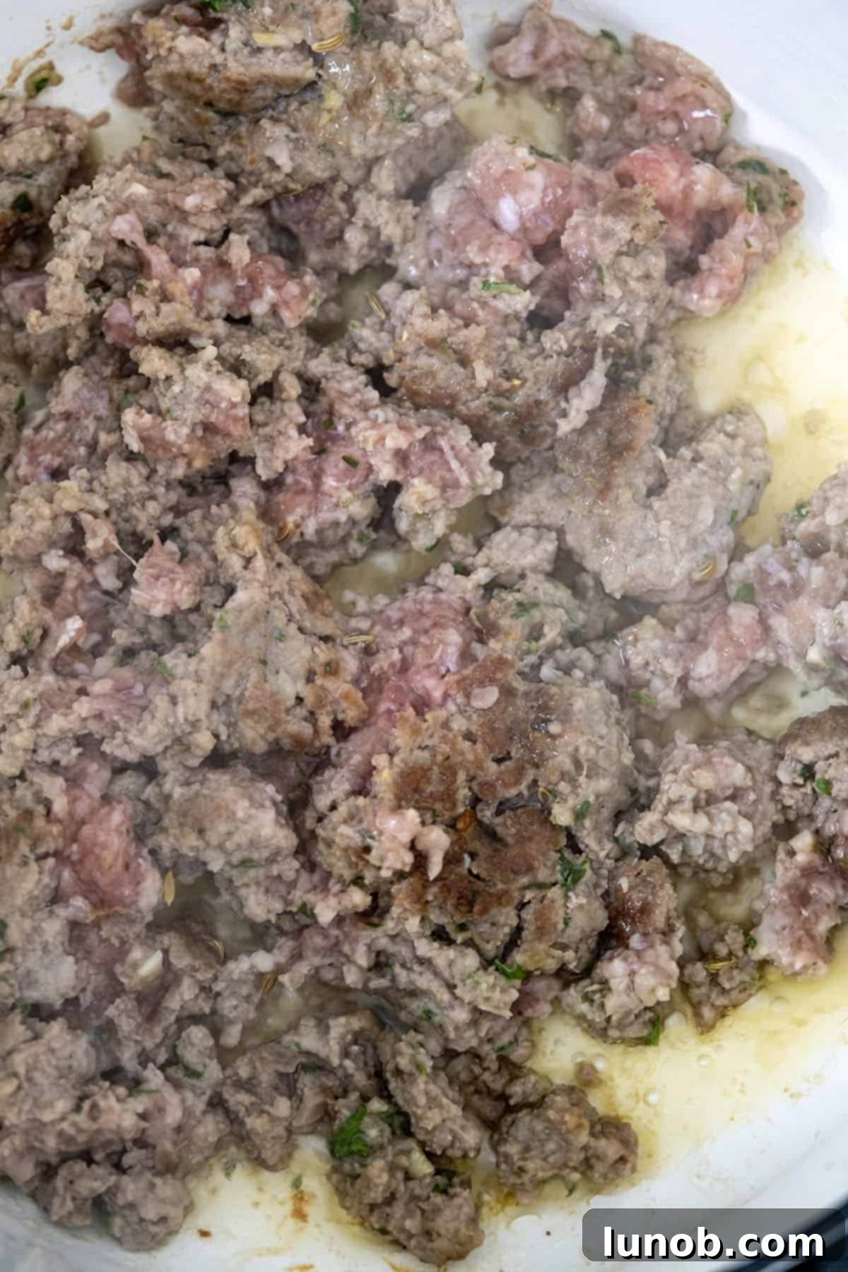 Ground Italian sausage browning in a Dutch oven with a small amount of oil.