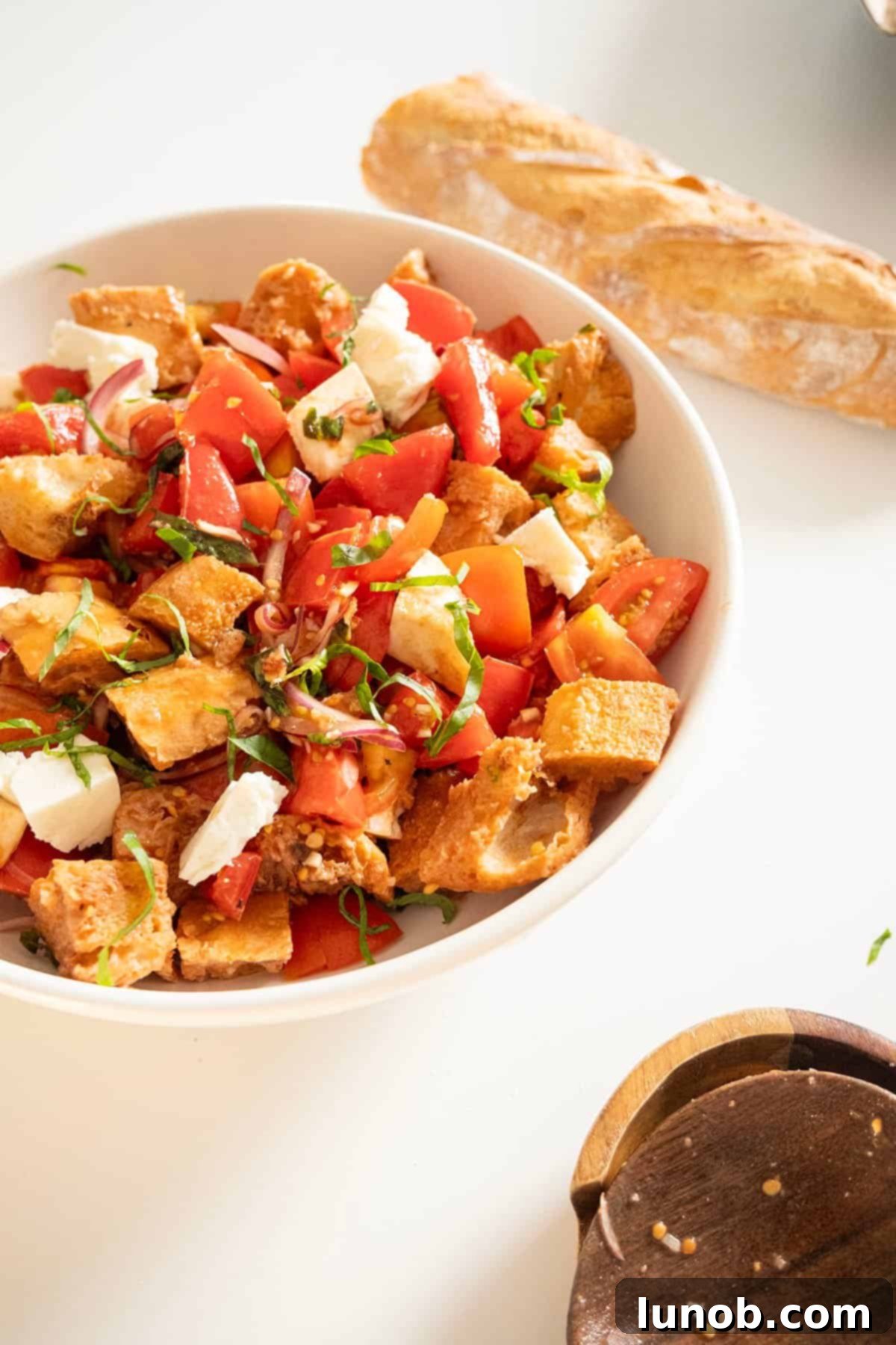 A vibrant Panzanella salad brimming with fresh tomatoes, basil, and bread cubes in a large ceramic bowl, ready to be served.