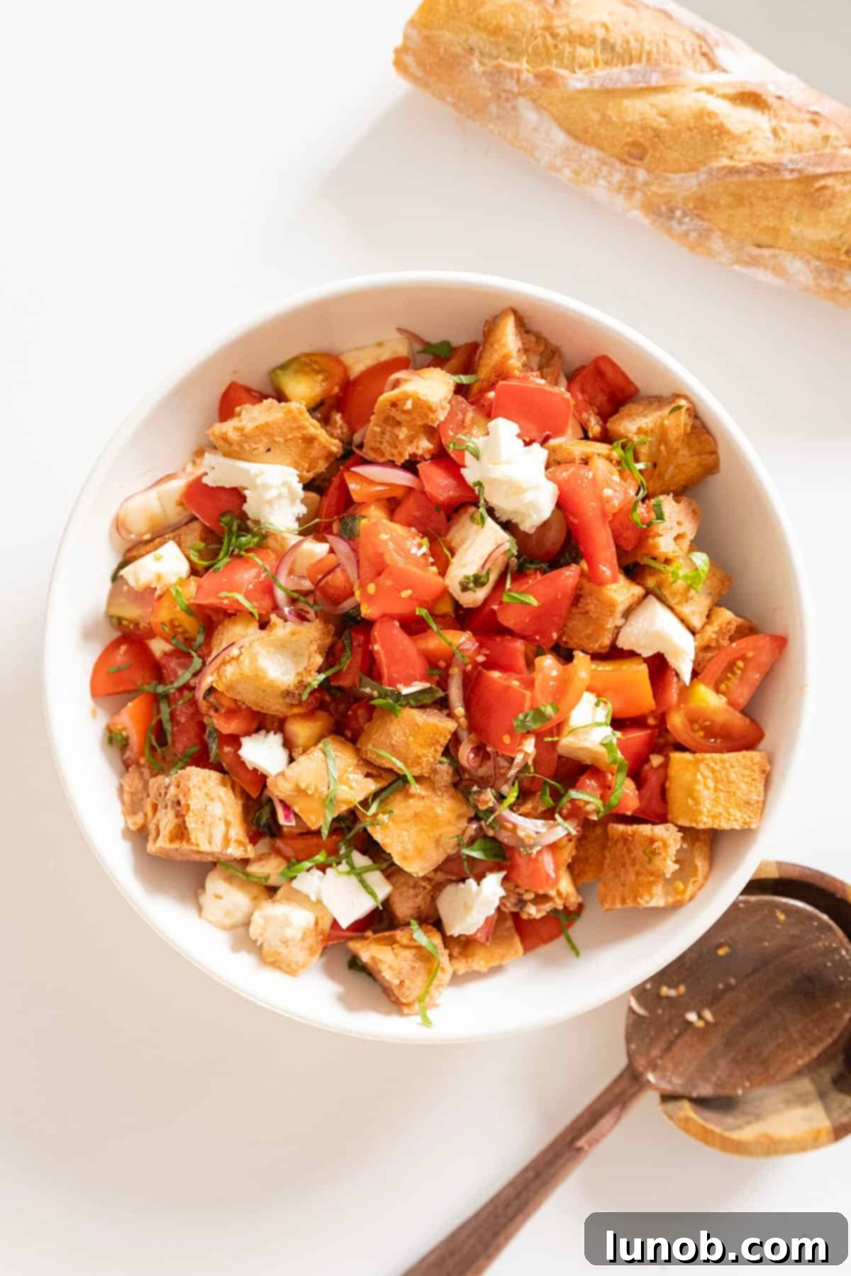 A freshly prepared Panzanella bread salad in a rustic ceramic bowl, garnished with basil leaves.