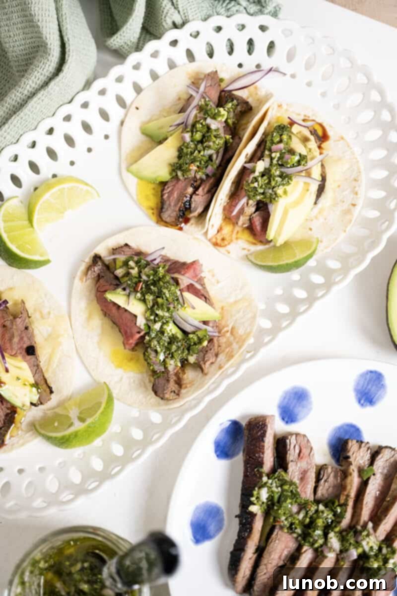 Vibrant Chimichurri Steak Tacos 2 Chimichurri steak tacos on a plate with limes, ready to be served.
