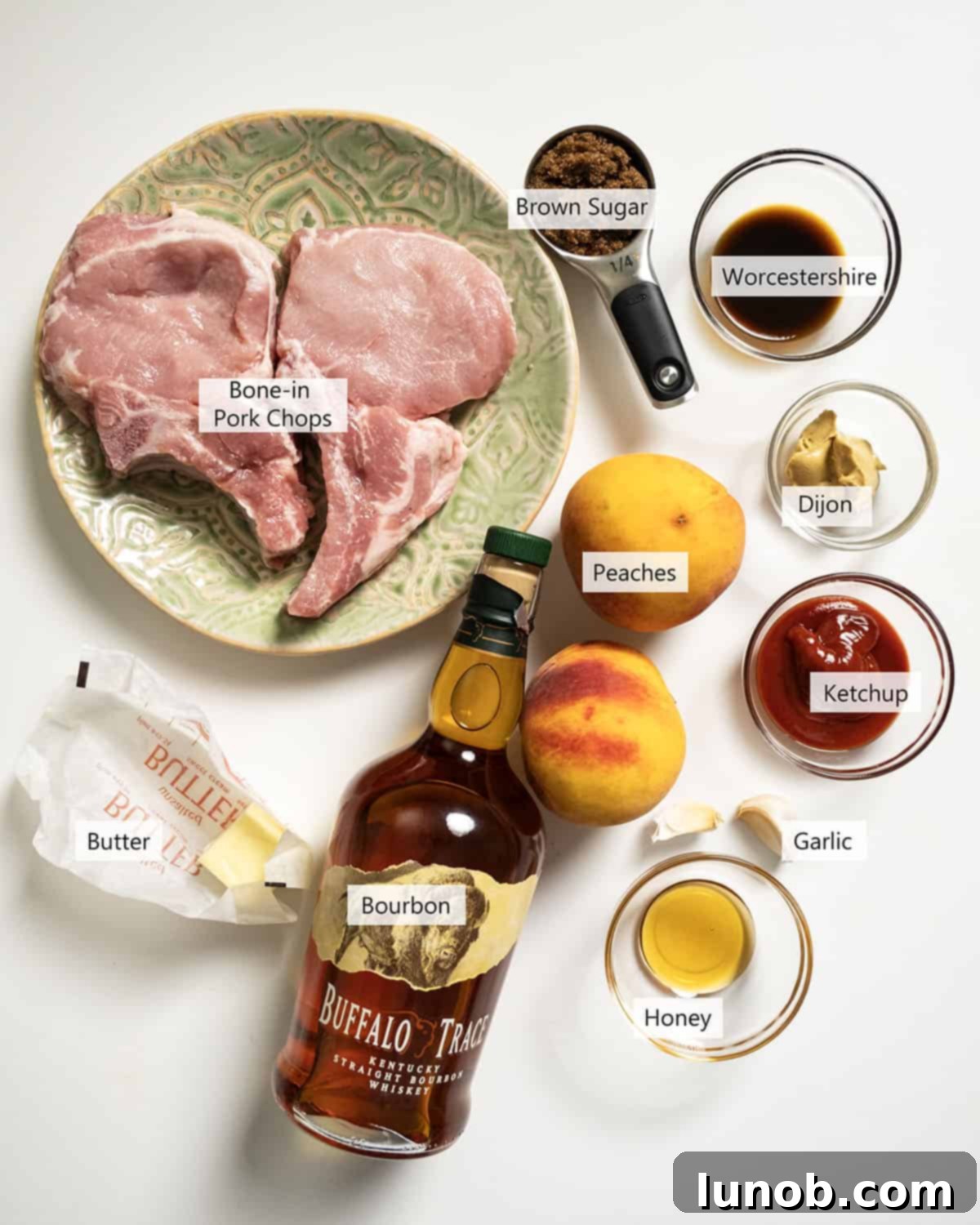 Fresh ingredients laid out for making the bourbon peach glazed pork chops, including peaches, garlic, butter, and sauces.