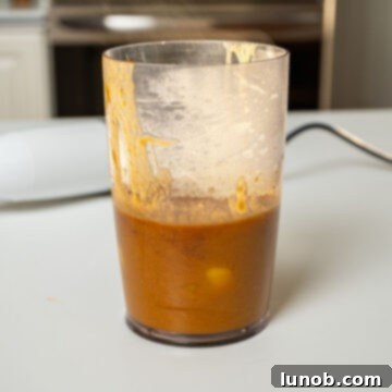 Smooth bourbon peach sauce, blended to perfection, resting in a measuring cup, ready for glazing.