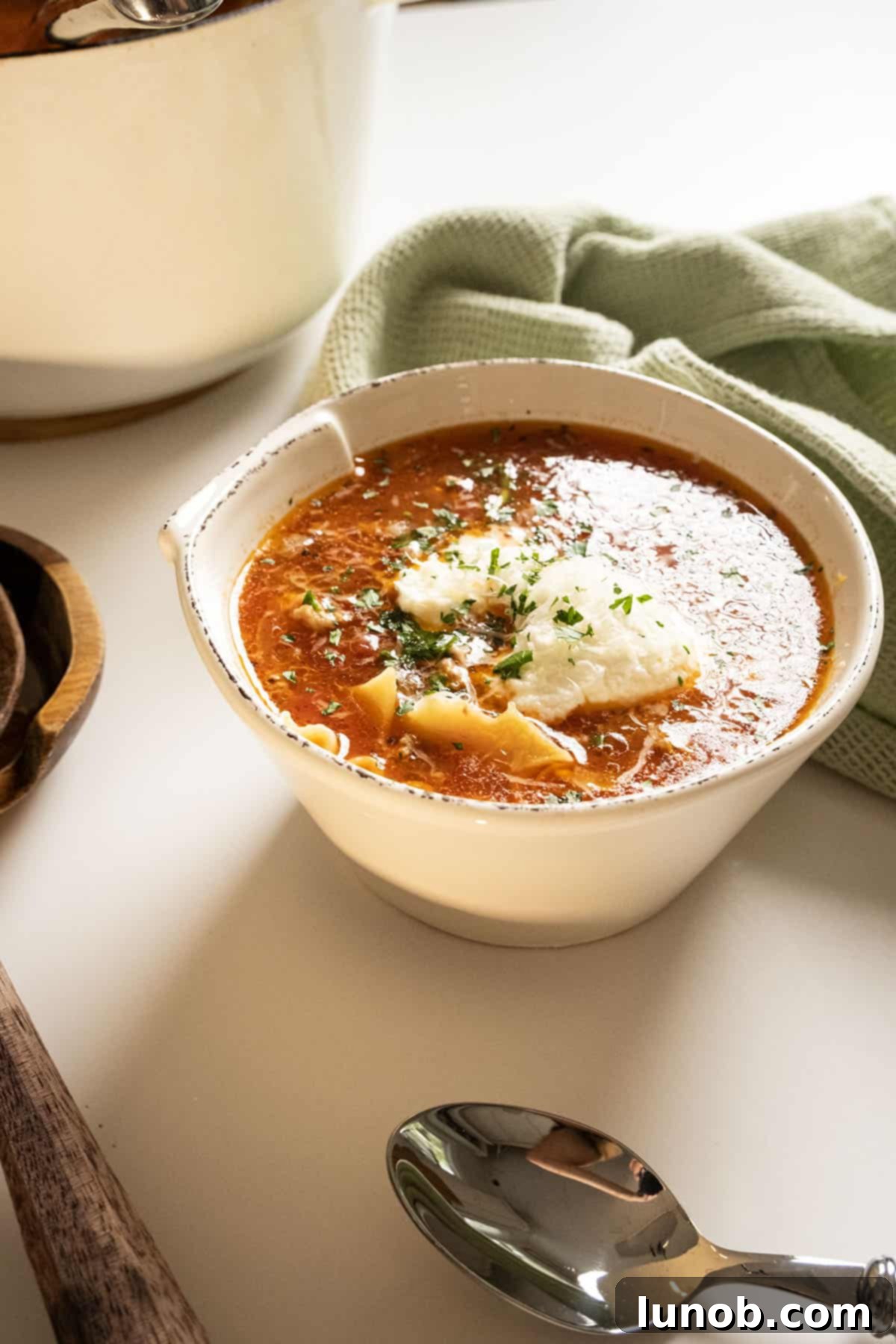 Ultimate One-Pot Lasagna Soup 2 A comforting bowl of One-Pot Lasagna Soup, garnished with a creamy dollop of ricotta, fresh parsley, and grated parmesan cheese, ready to be enjoyed.