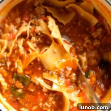 Ultimate One-Pot Lasagna Soup 11 Broken lasagna noodles being added to the simmering lasagna soup, ready to cook until tender.