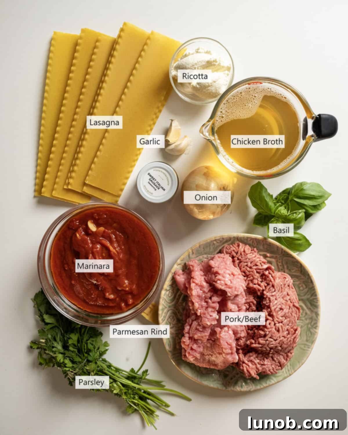 Ultimate One-Pot Lasagna Soup 3 A flat lay of fresh ingredients including ground meat, marinara, broth, onions, garlic, and fresh basil, ready for making lasagna soup.