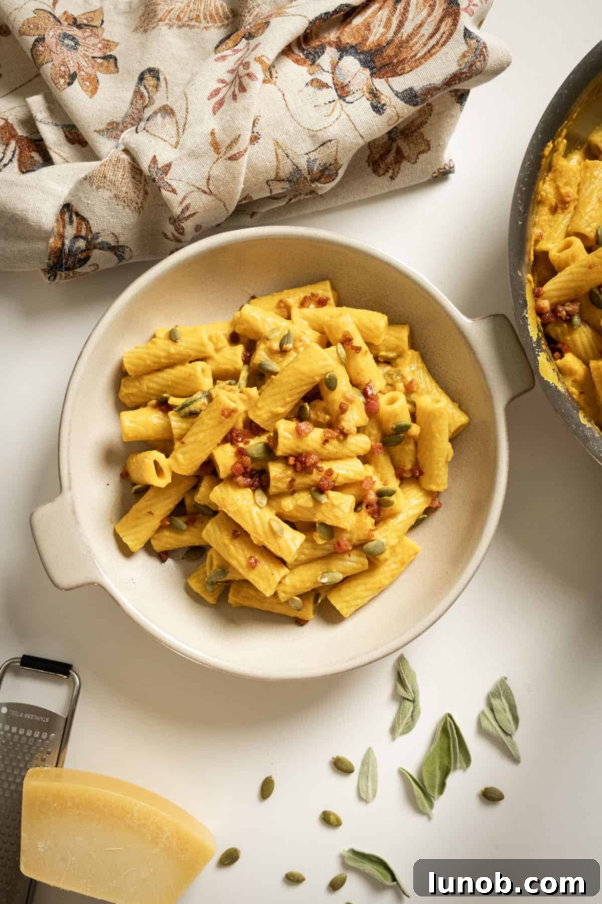 Velvety Pumpkin Pasta 2 A beautifully plated bowl of creamy pumpkin pasta, garnished with golden crispy pancetta and toasted pumpkin seeds, ready to be enjoyed.
