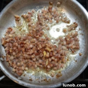 Velvety Pumpkin Pasta 5 Cubed pancetta frying in a saucepan, rendering its fat and becoming golden brown and crispy.