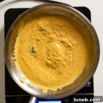 Velvety Pumpkin Pasta 9 Heavy cream and grated Parmesan cheese being stirred into the pumpkin pasta sauce off the heat to prevent curdling.