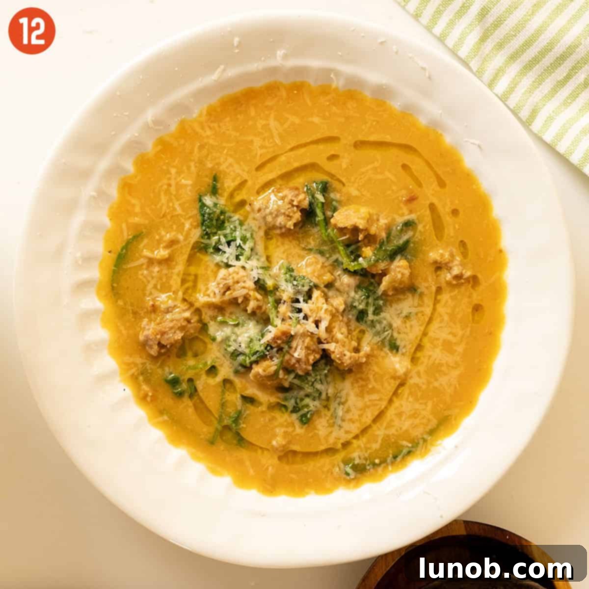 A close-up of a bowl of creamy butternut squash soup, garnished with parmesan cheese and a drizzle of olive oil.