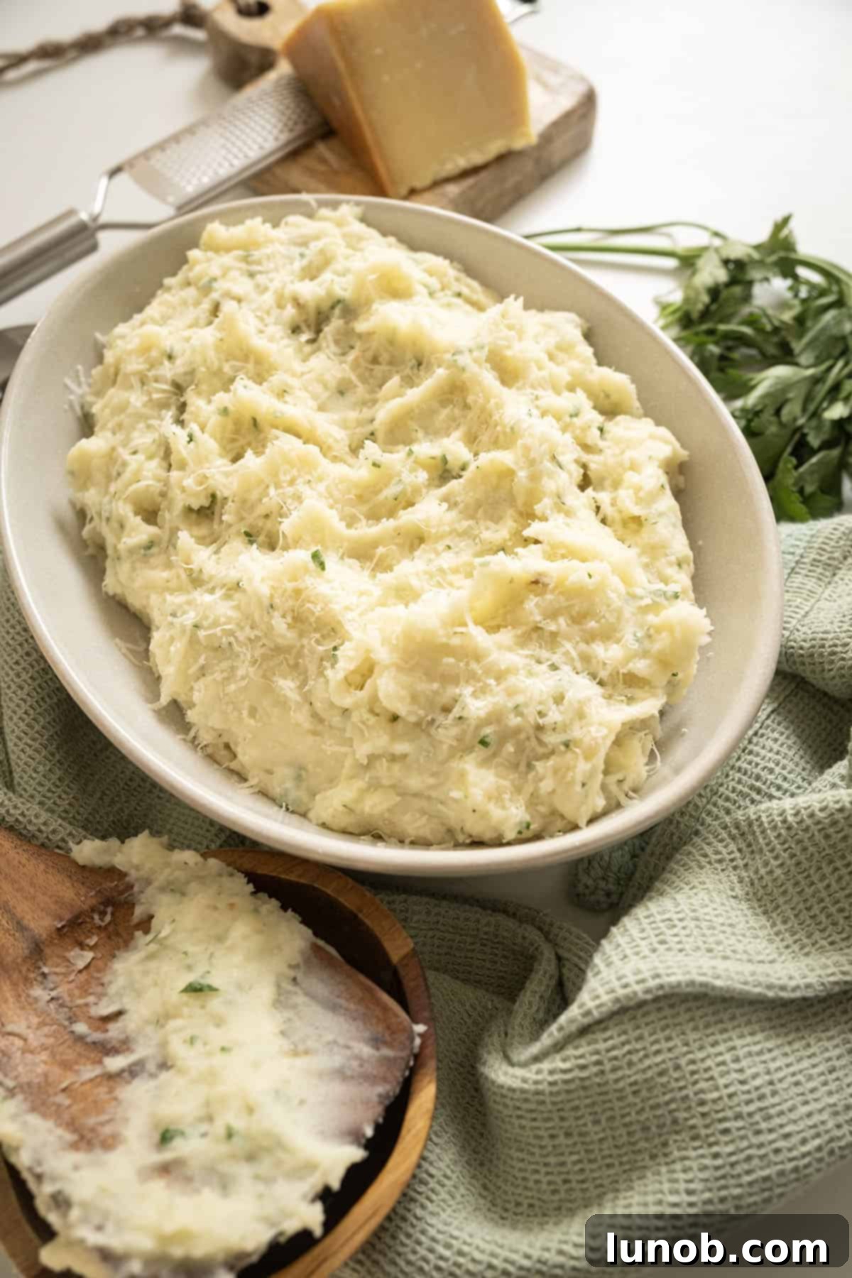 A large bowl of creamy garlic parmesan mashed potatoes, garnished with herbs.