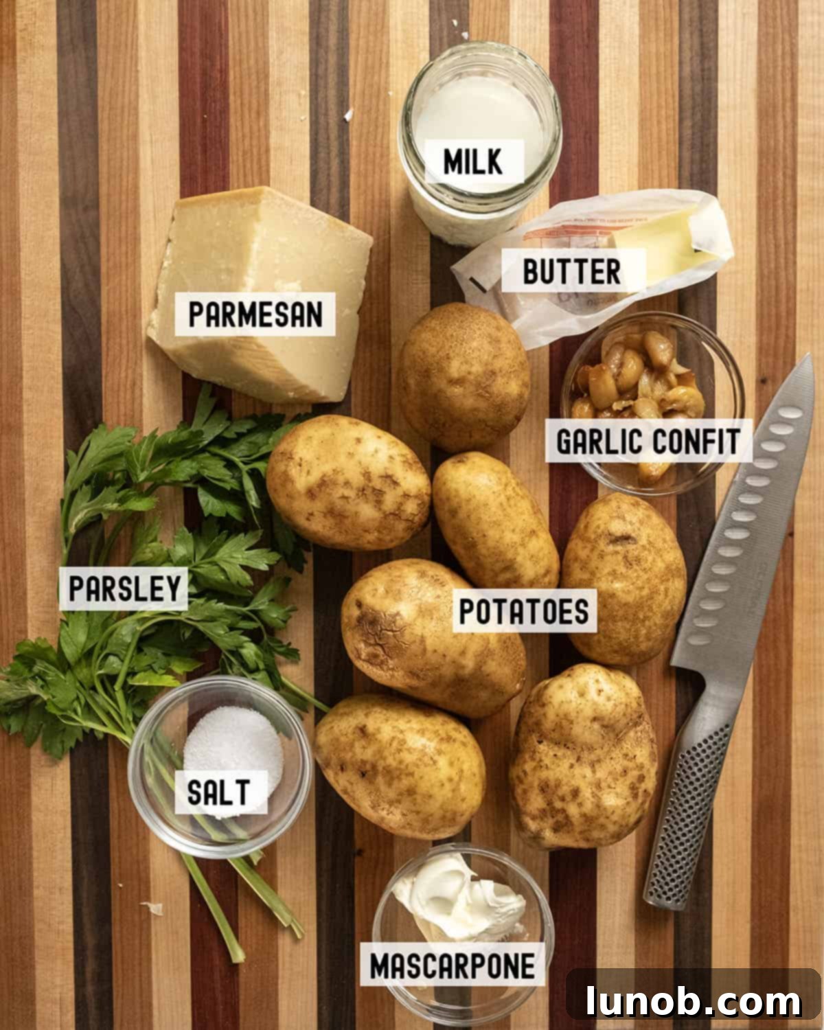 A collection of fresh ingredients laid out, including potatoes, garlic, parmesan, and herbs.