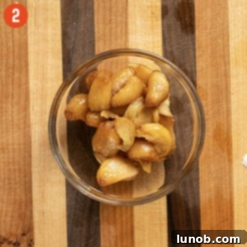 Mashed garlic confit in a small bowl, ready to be added to potatoes.
