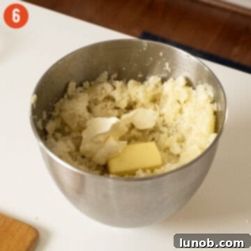 Mashed potatoes being combined with mascarpone, butter, and milk in a mixer.