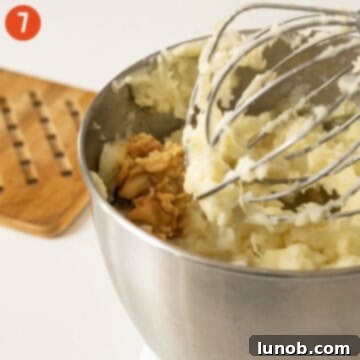 Garlic confit being folded into creamy mashed potatoes.