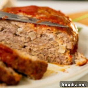 Italian meatloaf sliced on a plate, ready to be served with marinara sauce.