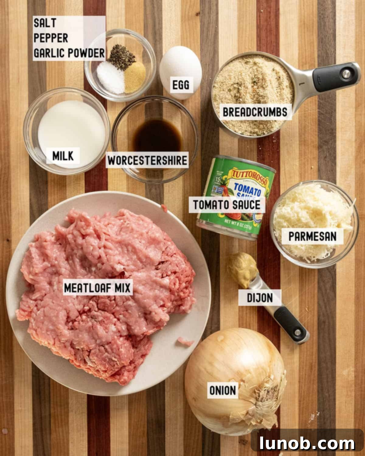 Fresh ingredients laid out for making Italian meatloaf: ground meat, onions, breadcrumbs, cheese, and herbs.