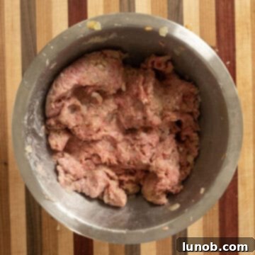 Hands gently mixing the Italian meatloaf ingredients in a bowl until just combined, ensuring not to overwork the mixture.