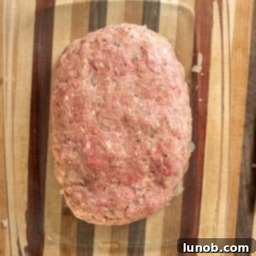 Italian meatloaf mixture shaped into an elongated loaf in a glass baking dish, ready for sauce.