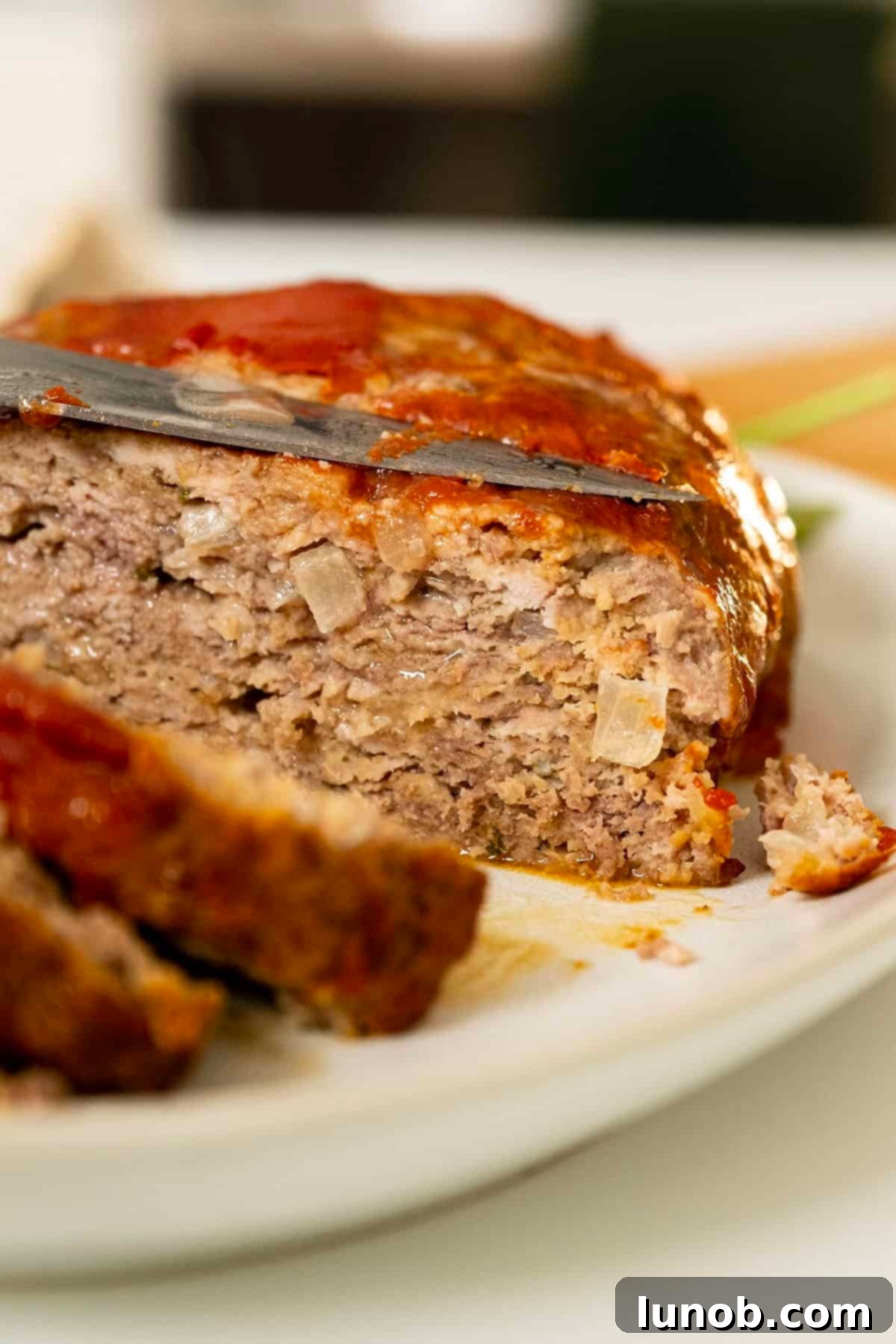 Perfectly baked Italian meatloaf, thickly sliced and ready to be served, showcasing its juicy interior and flavorful crust.