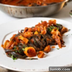 Ebony Ocean Pasta with Seared Calamari 11 Squid ink pasta with calamari on a plate.