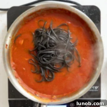 Ebony Ocean Pasta with Seared Calamari 9 Cooked squid ink pasta being transferred directly into the simmering calamari sauce.