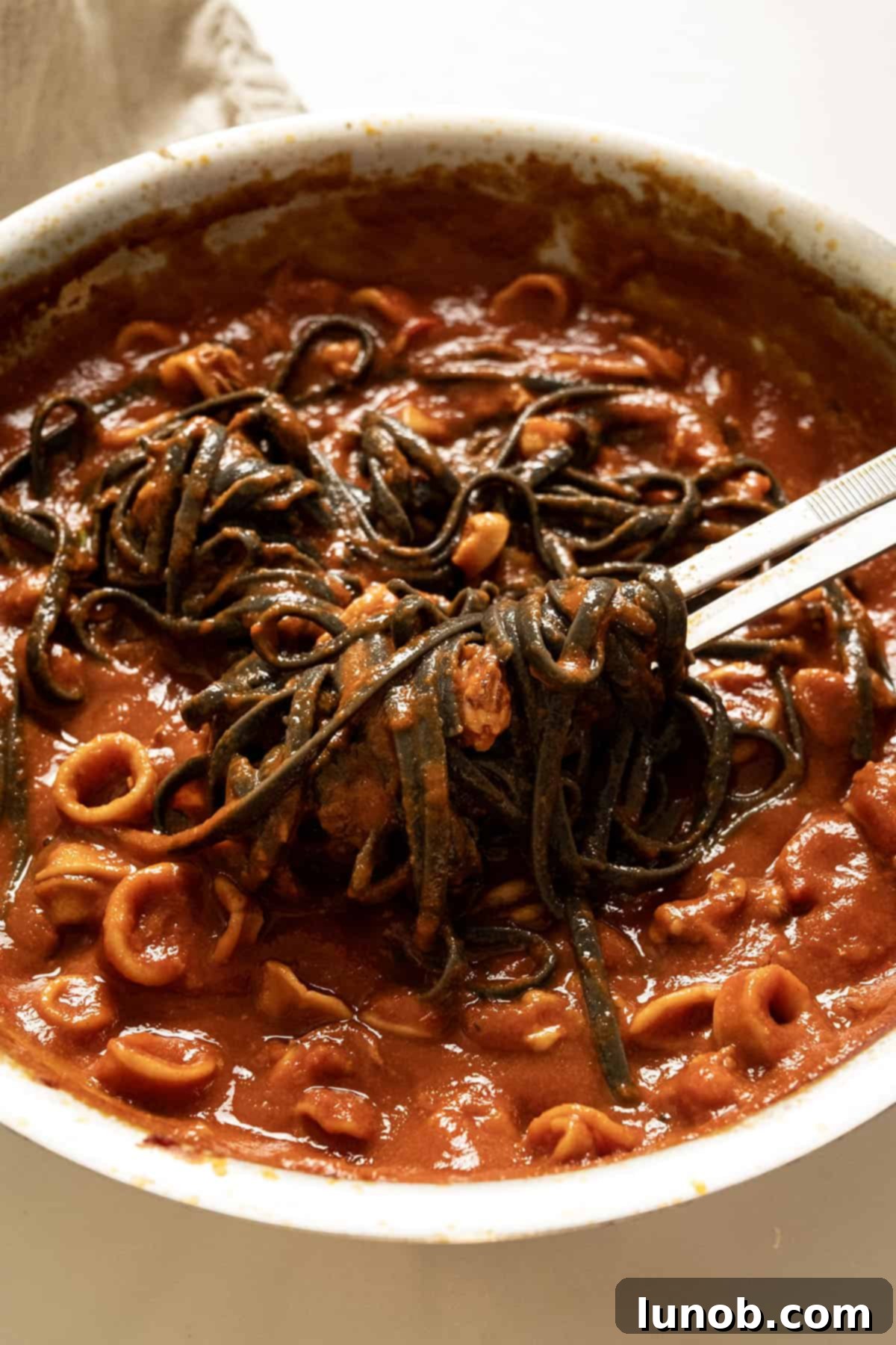 Ebony Ocean Pasta with Seared Calamari 10 Squid ink pasta with calamari and sauce tossed together in a large pan, ready to serve.