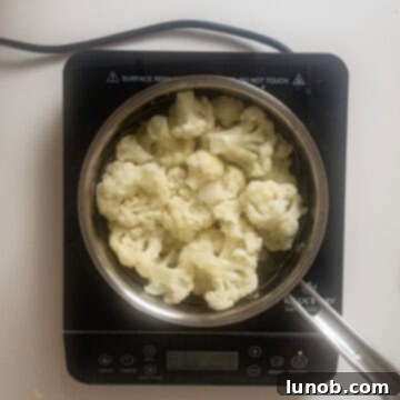 Crispy Cauliflower Fritters 4 Cauliflower in steamer basket in a pot.