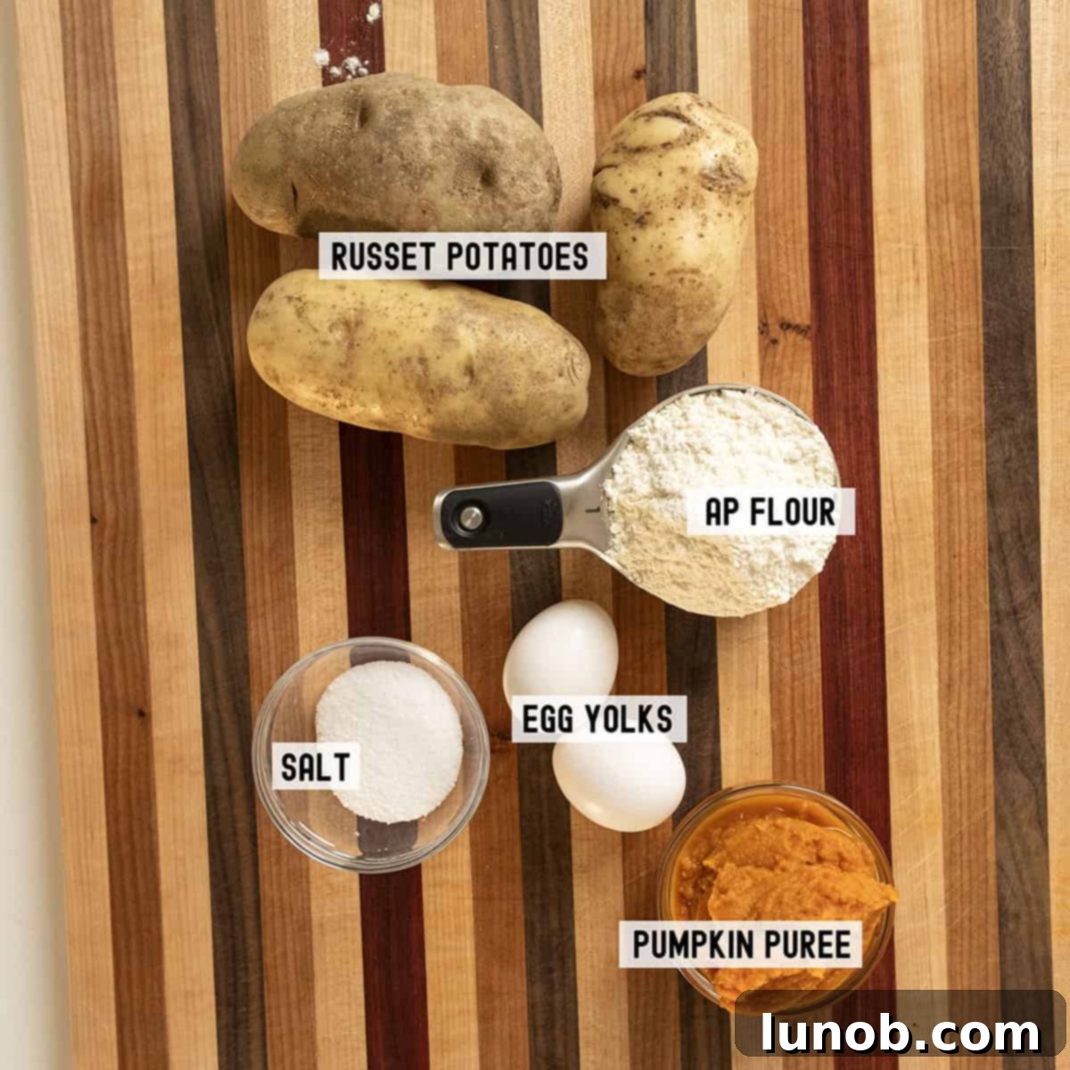 Ingredients laid out for making pumpkin gnocchi, including potatoes, pumpkin puree, eggs, flour, and salt.