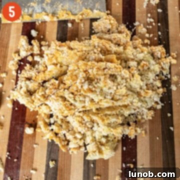 Using a bench scraper to chop flour, pumpkin puree, salt, egg yolk, and potato mixture together on a surface.
