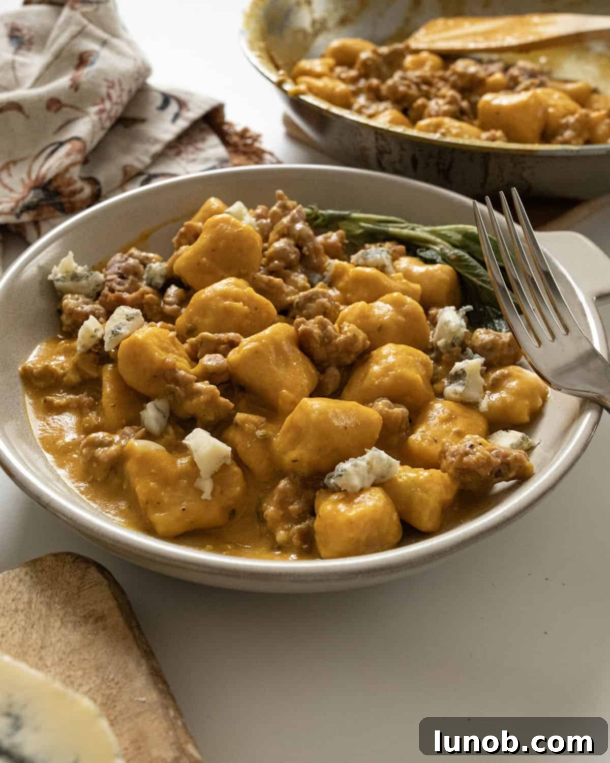 Pumpkin Gnocchi Perfection 11 A bowl of Gnocchi with pumpkin sauce and sausage, garnished with fresh herbs.