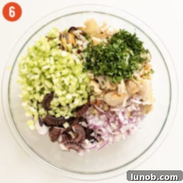 Freshly chopped celery, red onion, and minced garlic are being added to the bowl of mixed seafood.