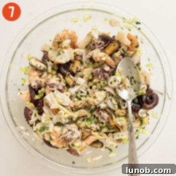 The Italian Seafood Salad, with all ingredients mixed, covered with plastic wrap and ready for marinating in the refrigerator.