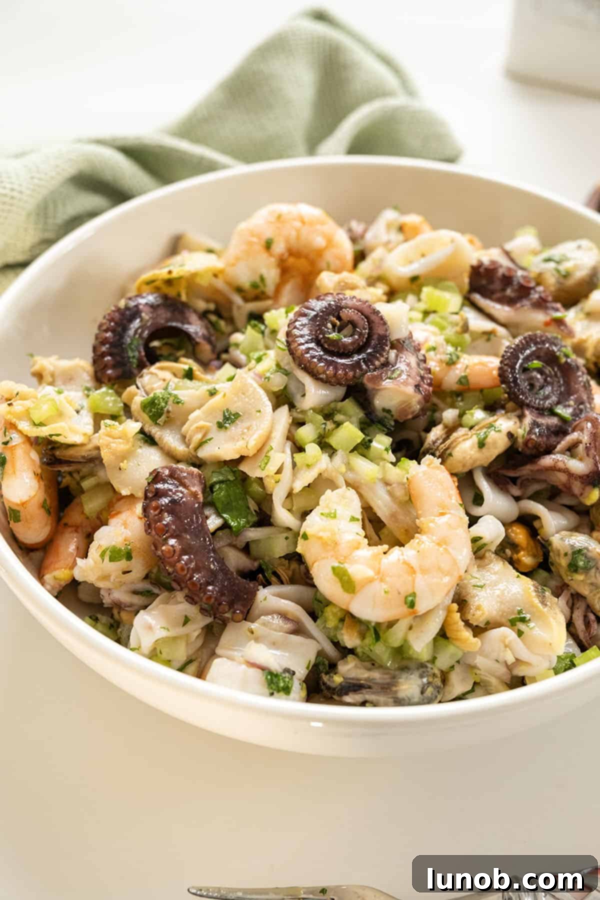 A large bowl of freshly prepared Italian Seafood Salad, garnished with fresh parsley, ready to be served.