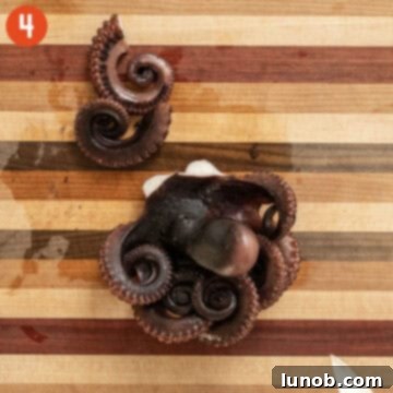 Chopping octopus tentacles on a wooden cutting board, preparing them for the Italian Seafood Salad.